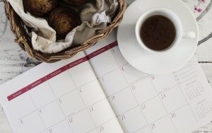 Upcoming Exhibits - Calendar with a cup of coffee and a muffin